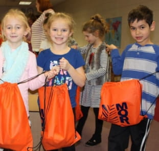 Children from Concord Elementary School holding MOR Construction blessing bags for Martin Luther King Day charity event in Chester.